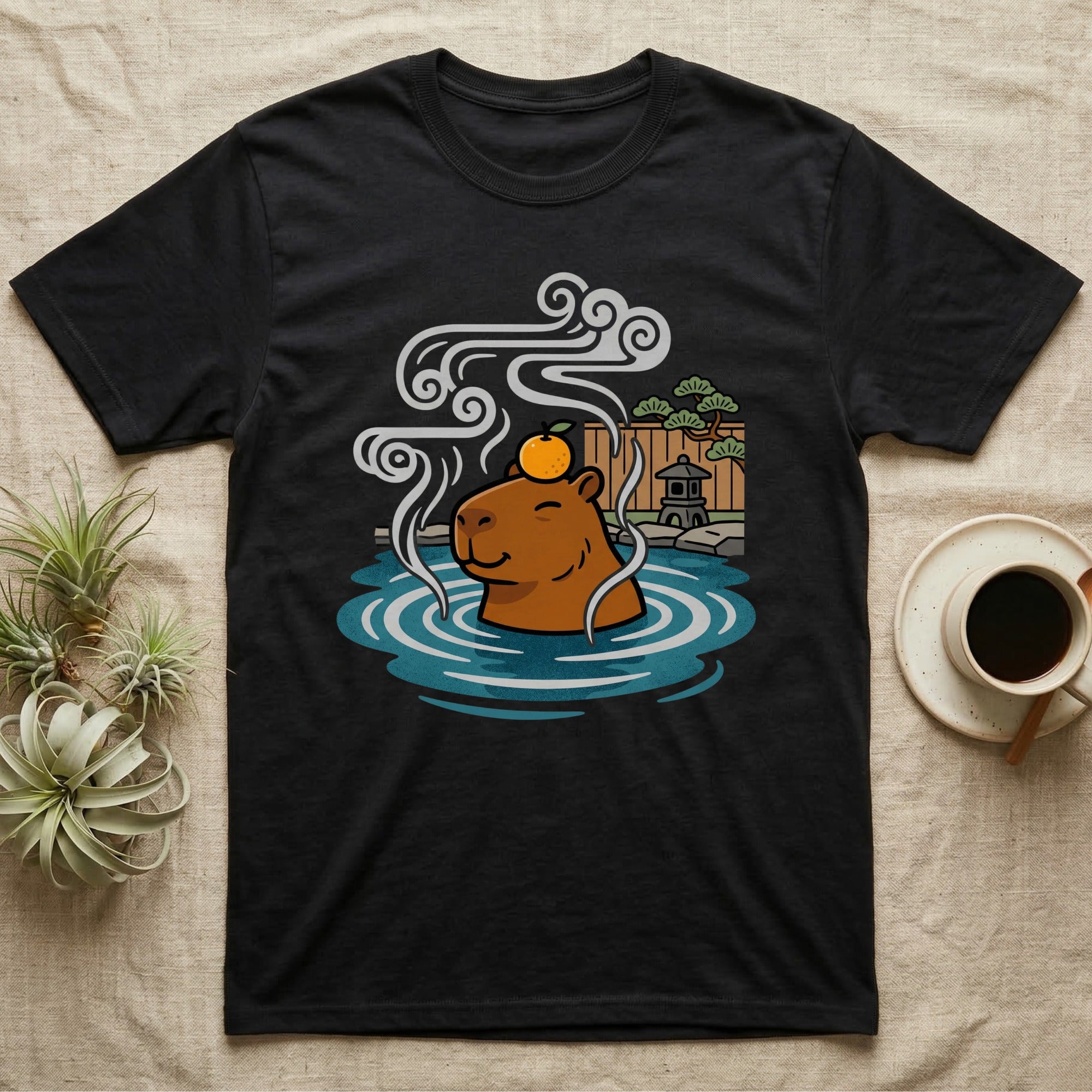 Black t-shirt with cartoon capybara wearing an orange slice relaxing in a hot spring.