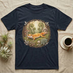 Dark t-shirt featuring a whimsical illustration of a gecko among ferns and mushrooms.
