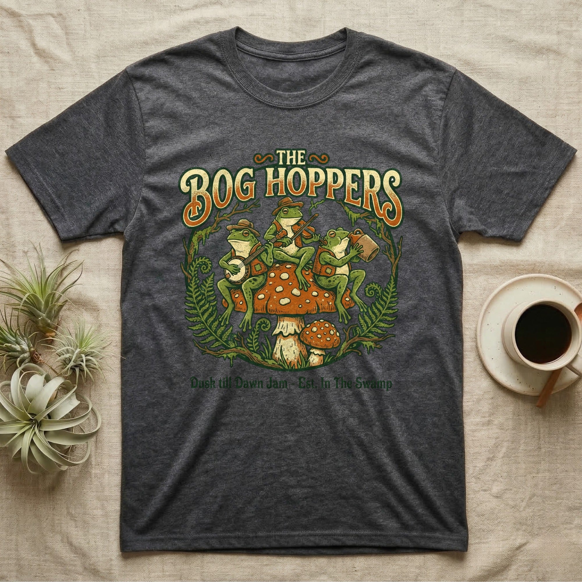 The Bog Hoppers t-shirt features frogs playing instruments on mushrooms, with text.