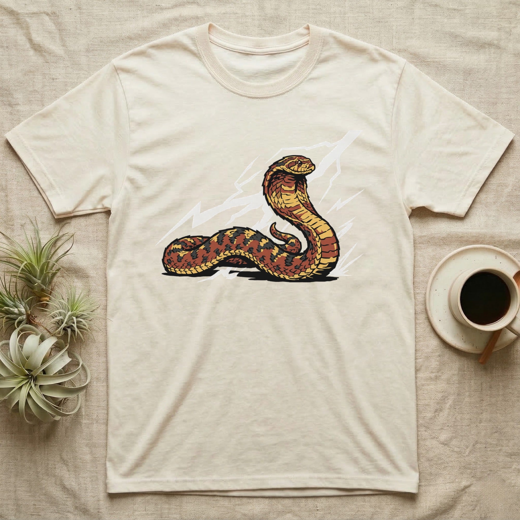 Cream t-shirt with a stylized cobra illustration featuring lightning bolts.
