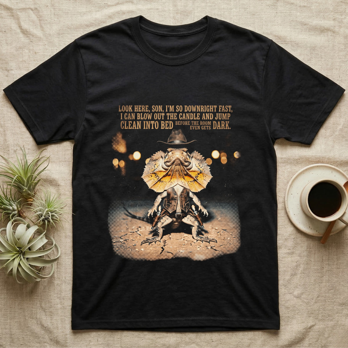 Frilled Lizard Cowboy T-Shirt in Black — Frilled lizard dressed as a Wild West cowboy with a Stetson and twin holsters under a tall-tale quote in distressed halftone.