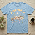 African Fat-Tailed Gecko Softie T-Shirt in Light Blue — African fat-tailed gecko with a plump tail under a puffy pastel "just thicc" bubble wordmark with tiny hearts.