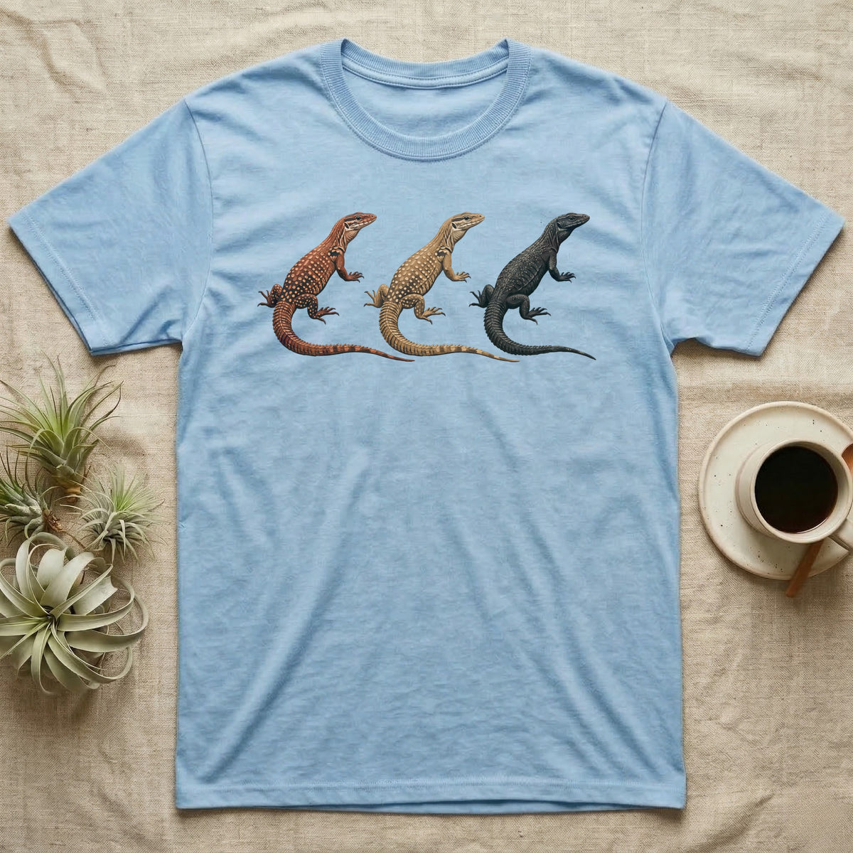 Ackie Monitor Triptych T-Shirt in Light Blue — Three ackie monitors in a row, painted in thick impasto — red, yellow and dark island forms with pale ocelli.