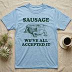Blue Tongue Skink Sausage T-Shirt in Light Blue — Antique-engraved blue-tongued skink facing forward, with the word SAUSAGE above and a two-line caption below.