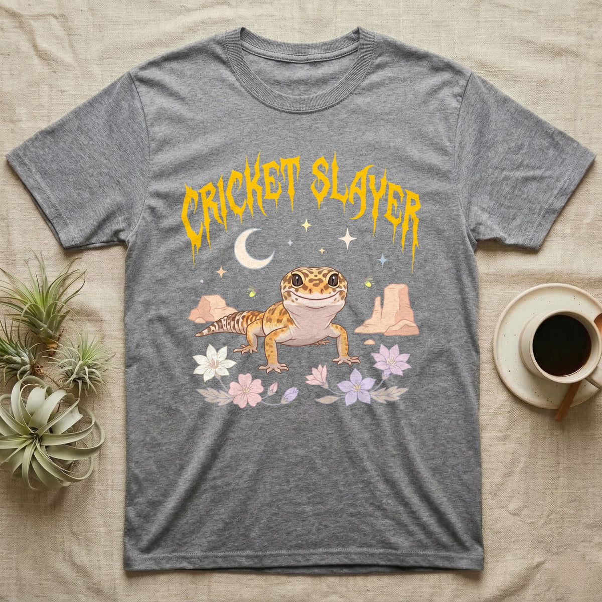 Leopard Gecko Feral T-Shirt in Sport Grey — Smiling leopard gecko in a pastel desert-night scene under a spiky golden metal wordmark reading CRICKET SLAYER.