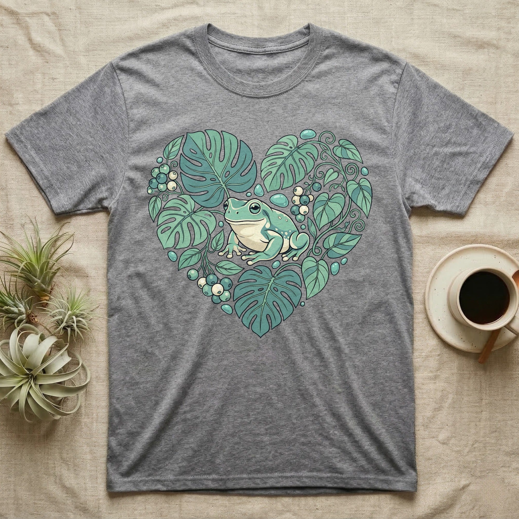 Gray t-shirt with a frog surrounded by green monstera leaves in a heart shape.