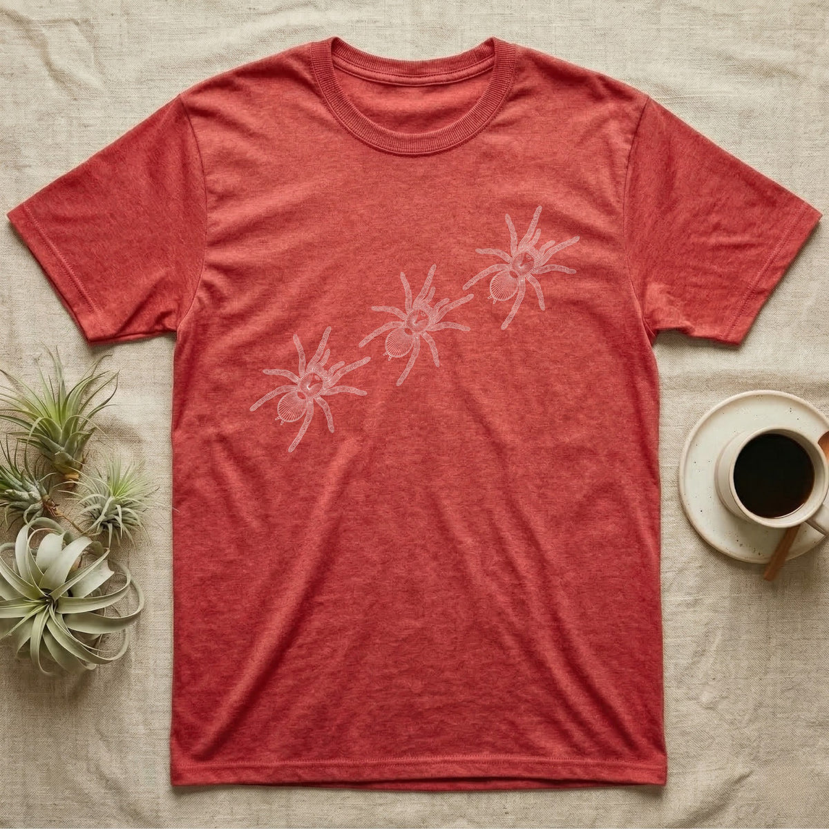 Tarantula Migration Trio T-Shirt in Heather Red — Three tarantulas drawn in fine pale outline, seen from above, walking on a rising diagonal across flat grey.