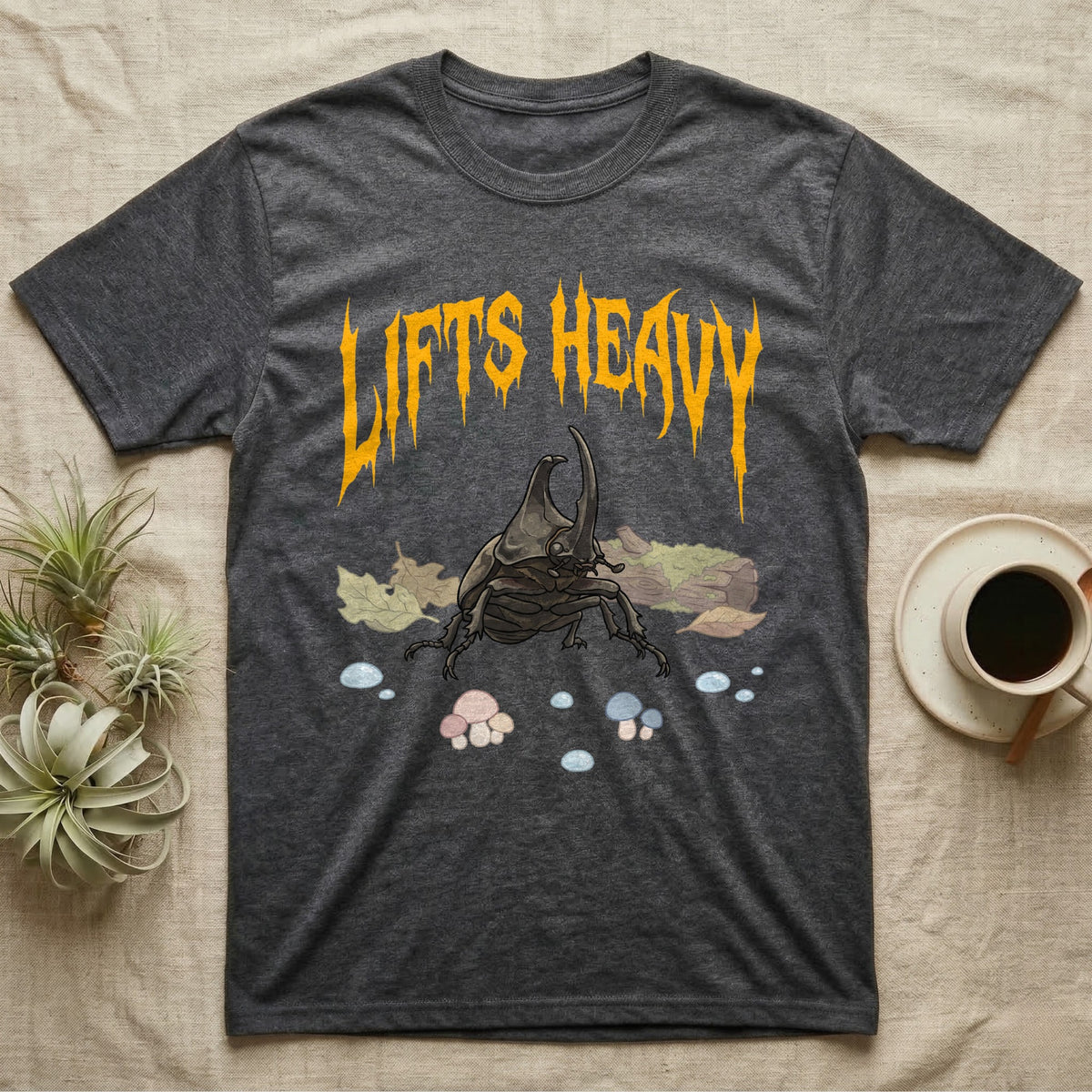 Rhino Beetle Feral T-Shirt in Dark Heather — Horned rhinoceros beetle standing head-on below a dripping amber-gold metal "Lifts Heavy" wordmark