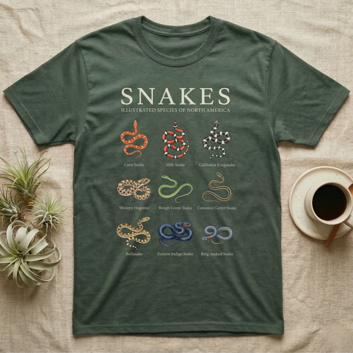Snake Species Chart T-Shirt in Military Green — Watercolour chart of nine named North American snakes under a cream serif Snakes title on charcoal grey