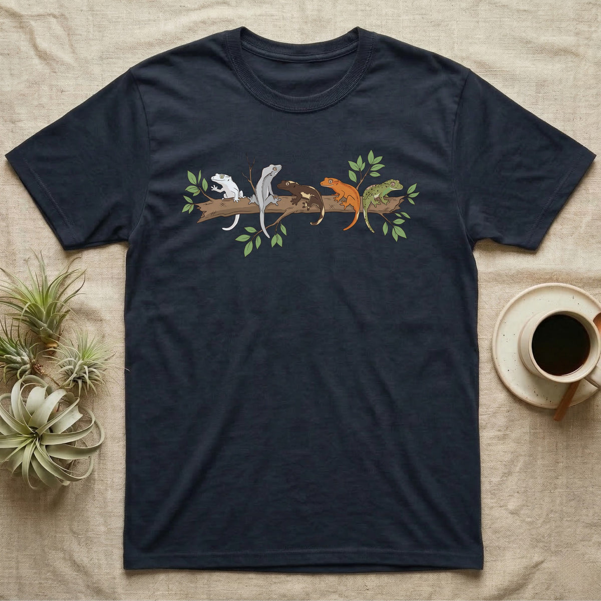 Crested Gecko Morph Line T-Shirt in Navy — Five crested gecko morphs in ink and watercolour perched along one cork bark branch with ficus leaves.