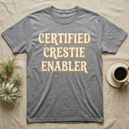 Certified Crestie Enabler T-Shirt in Sport Grey — Bold retro drop-shadow wordmark reading "Certified Crestie Enabler" in cream and ochre on a grey background.