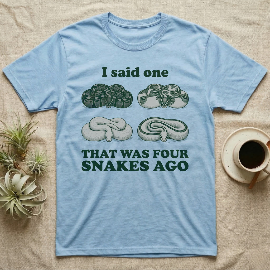 Ball Python Collector T-Shirt in Light Blue — Four engraved ball python morphs in tight coils between the words I said one and THAT WAS FOUR SNAKES AGO.