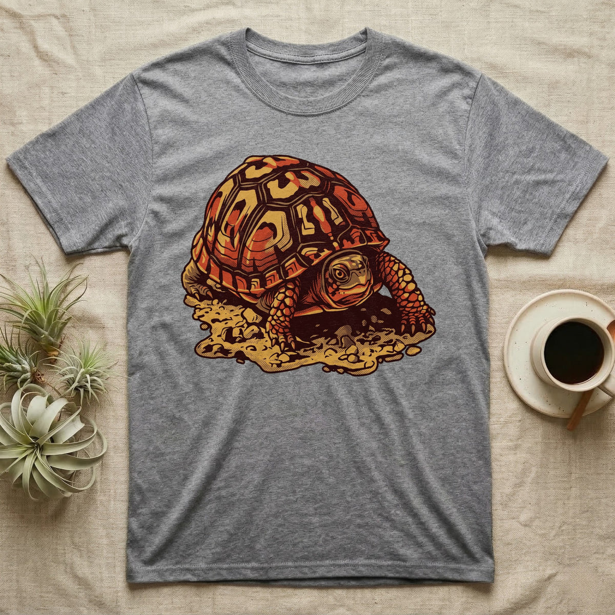 Vintage ink illustration of an Eastern box turtle crawling across sandy pebbles, high-domed shell shown in rust-red and amber, no on-shirt text. — shown on a Sport Grey tee.