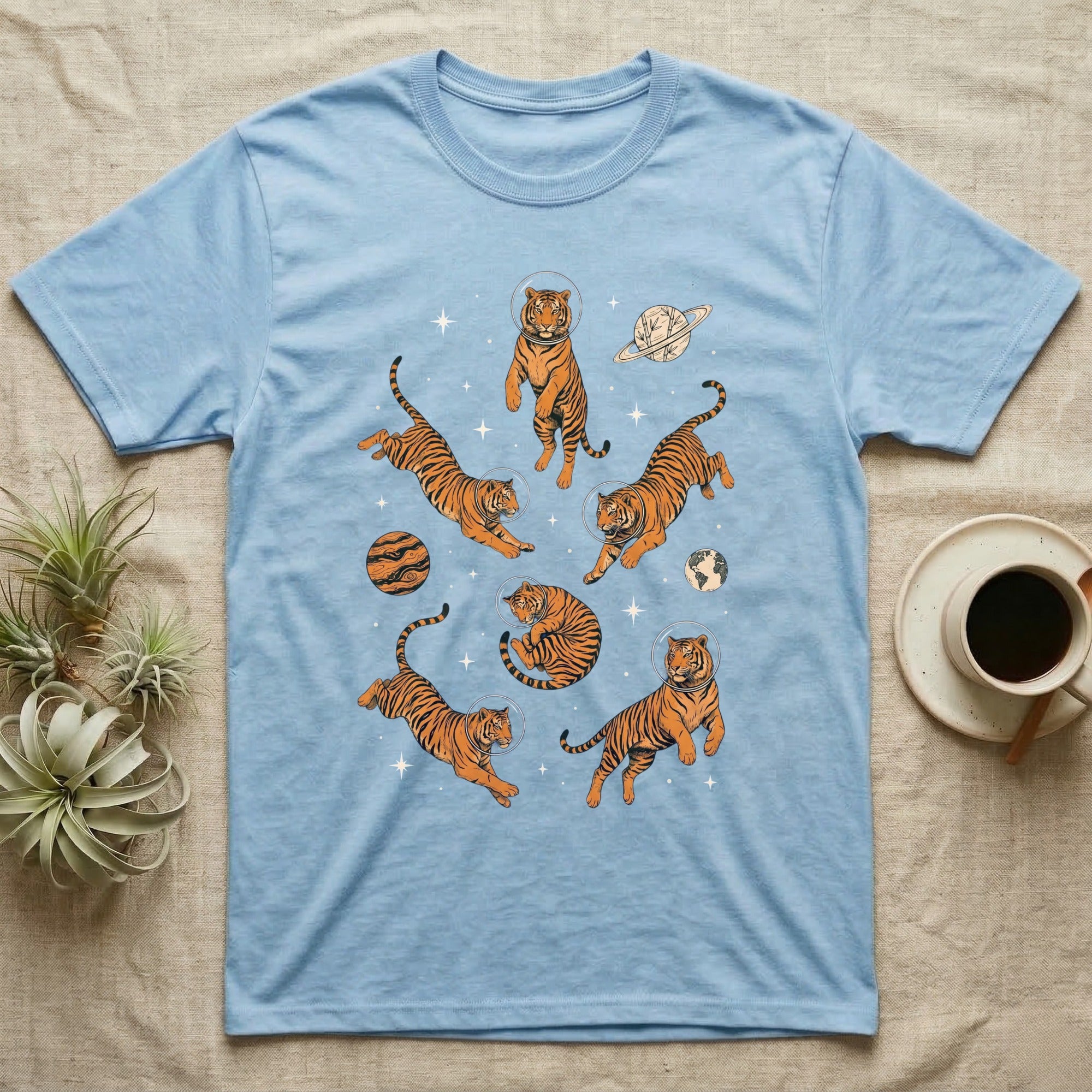 Light blue t-shirt with floating tigers in space with planets.