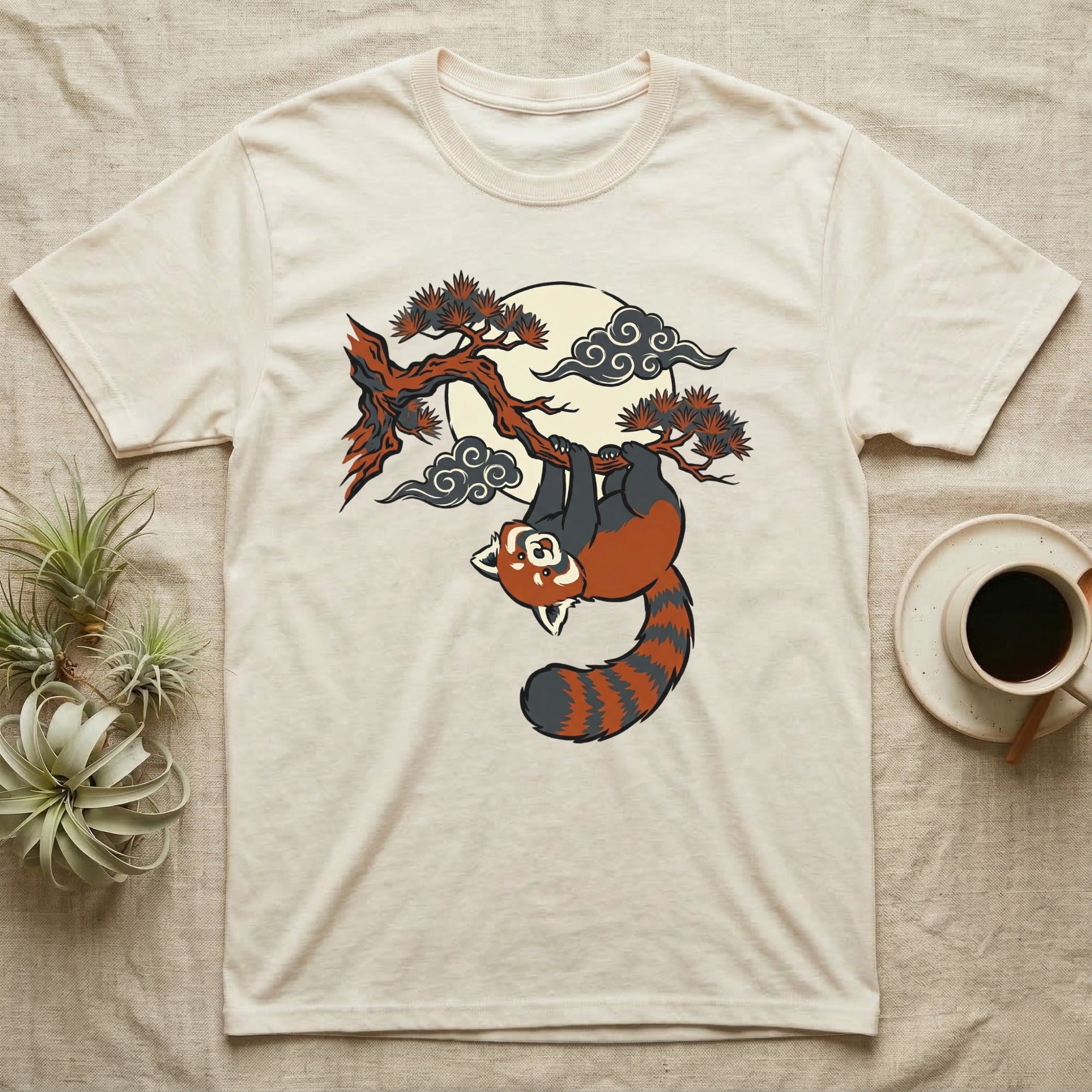 Cream t-shirt with red panda hanging from tree branch under moon.