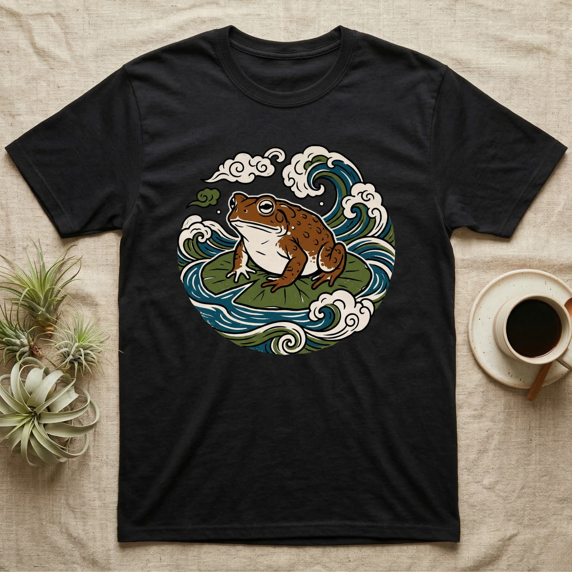 Black t-shirt with frog on lily pad and wave graphic.