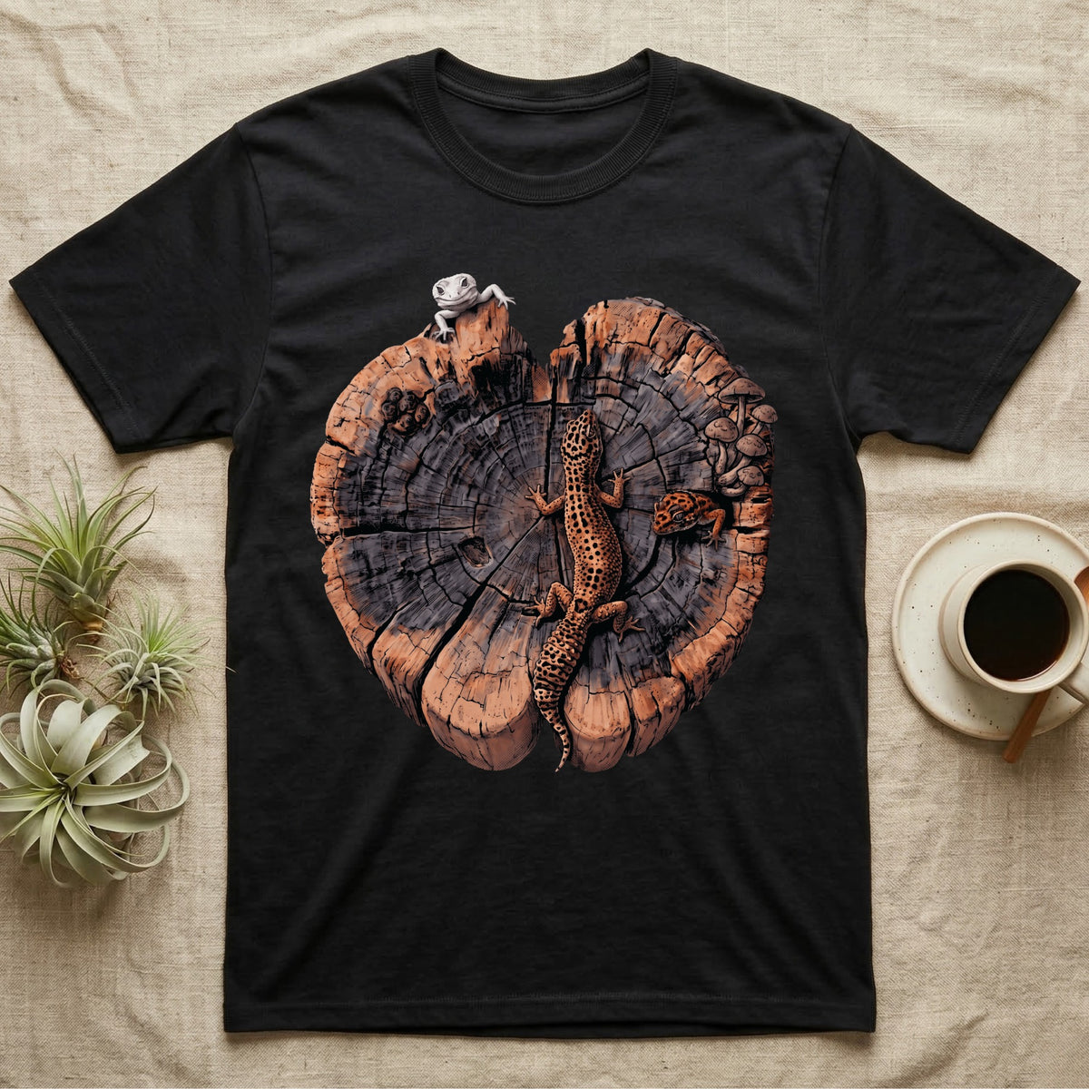 Leopard Gecko Stump Trio T-Shirt in Black — Three leopard geckos including a leucistic white morph on a cross-section log slab of amber growth rings with mushrooms, no on-shirt text.