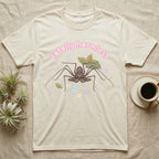 Tailless Whip Scorpion Baby T-Shirt in Natural — Pastel tailless whip scorpion with long whip legs among leaves and blossoms, puffy pink wordmark "totally harmless" above.
