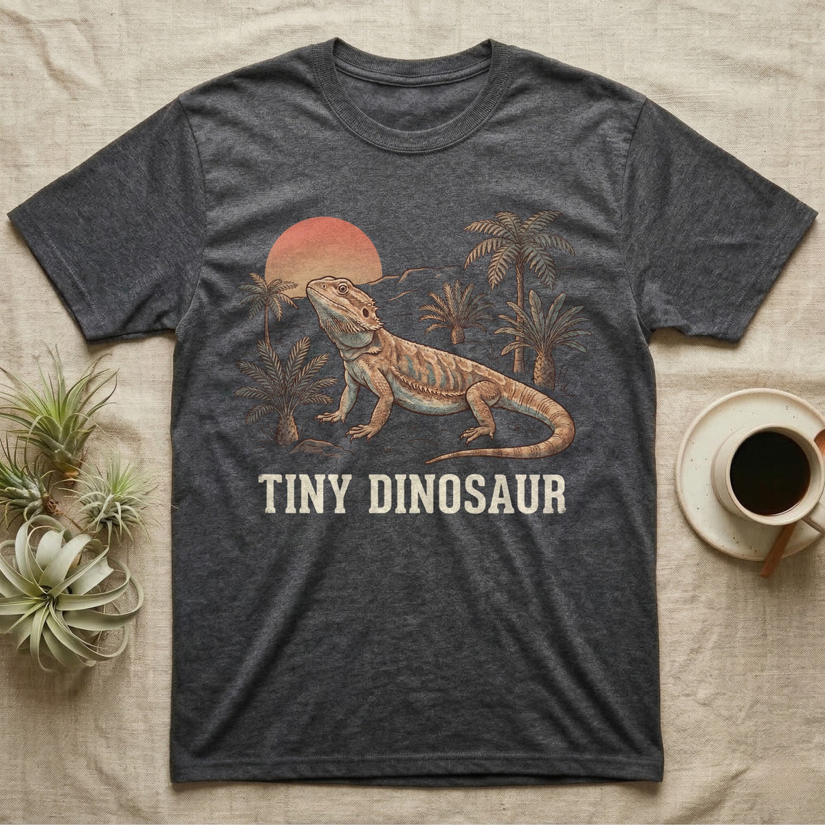 Tiny Dinosaur Bearded Dragon T-Shirt in Dark Heather — Retro natural-history illustration of a bearded dragon in profile in a prehistoric landscape with a distressed "Tiny Dinosaur" caption.