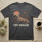 Tiny Dinosaur Bearded Dragon T-Shirt in Dark Heather — Retro natural-history illustration of a bearded dragon in profile in a prehistoric landscape with a distressed "Tiny Dinosaur" caption.