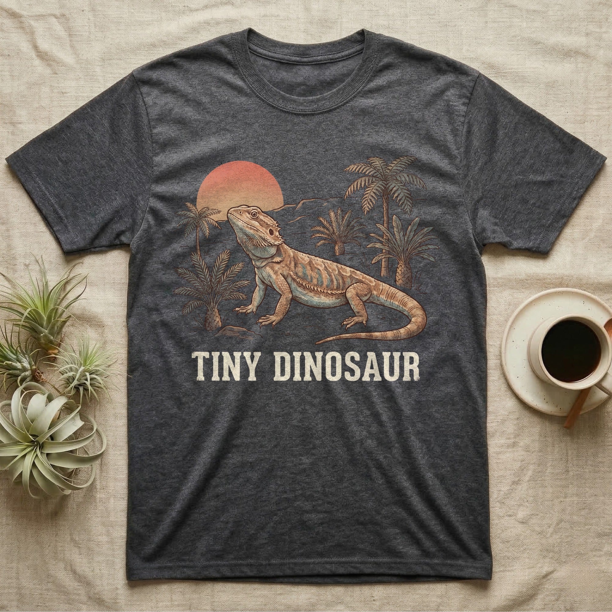 Tiny Dinosaur Bearded Dragon T-Shirt in Dark Heather — Retro natural-history illustration of a bearded dragon in profile in a prehistoric landscape with a distressed "Tiny Dinosaur" caption.