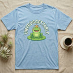 Light blue t-shirt with a smiling frog wearing a crown on a lily pad.