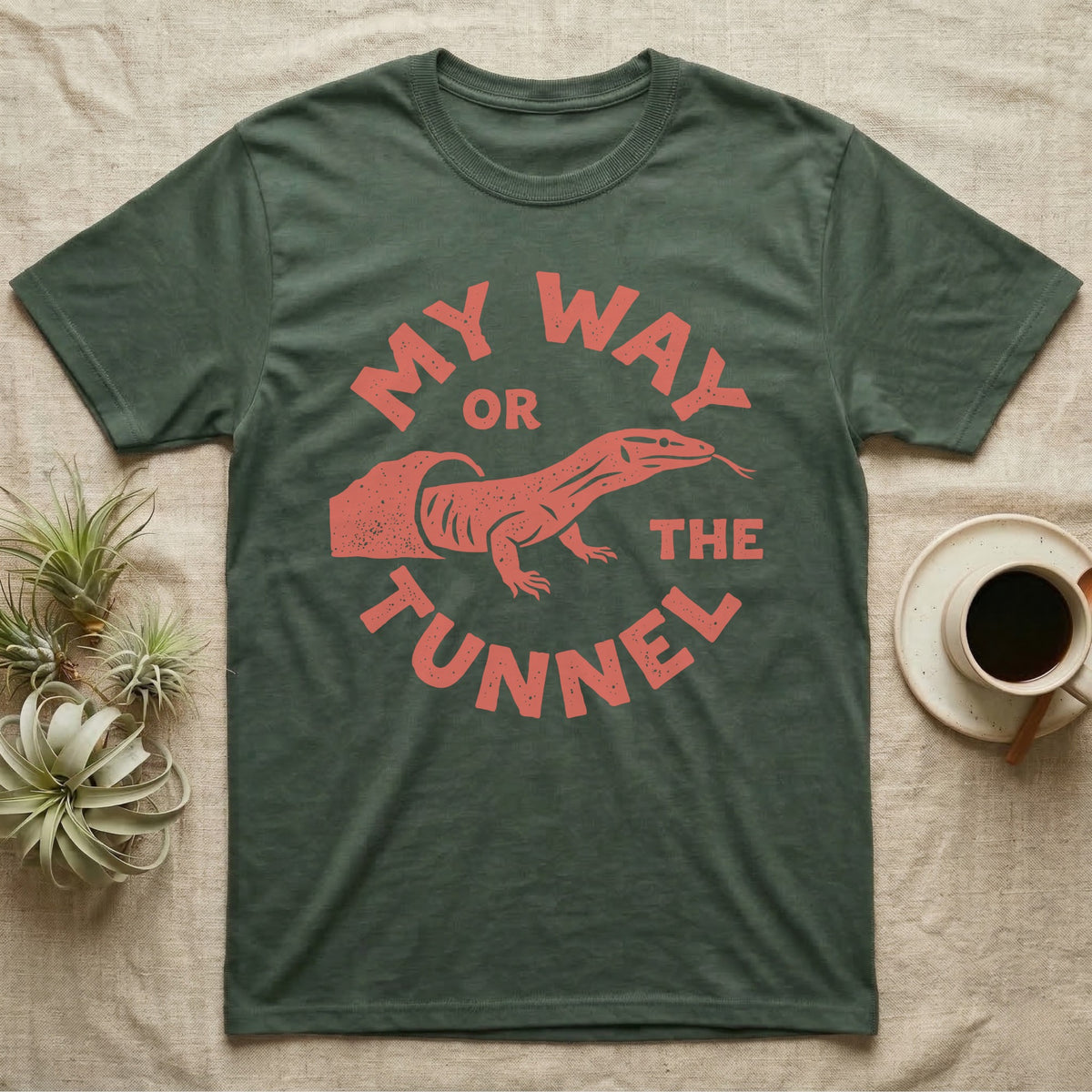 Ackie Monitor Tunnel T-Shirt in Military Green — Carved one-ink badge of an ackie monitor emerging from its sand tunnel, tongue out, ringed by the words MY WAY OR THE TUNNEL