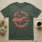 Ackie Monitor Tunnel T-Shirt in Military Green — Carved one-ink badge of an ackie monitor emerging from its sand tunnel, tongue out, ringed by the words MY WAY OR THE TUNNEL