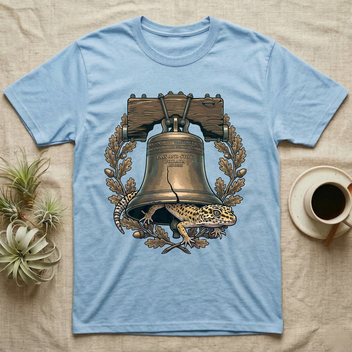 Leopard Gecko Liberty Bell T-Shirt in Light Blue — Engraved leopard gecko emerging beneath the bronze Liberty Bell inside an oak-leaf and acorn wreath.