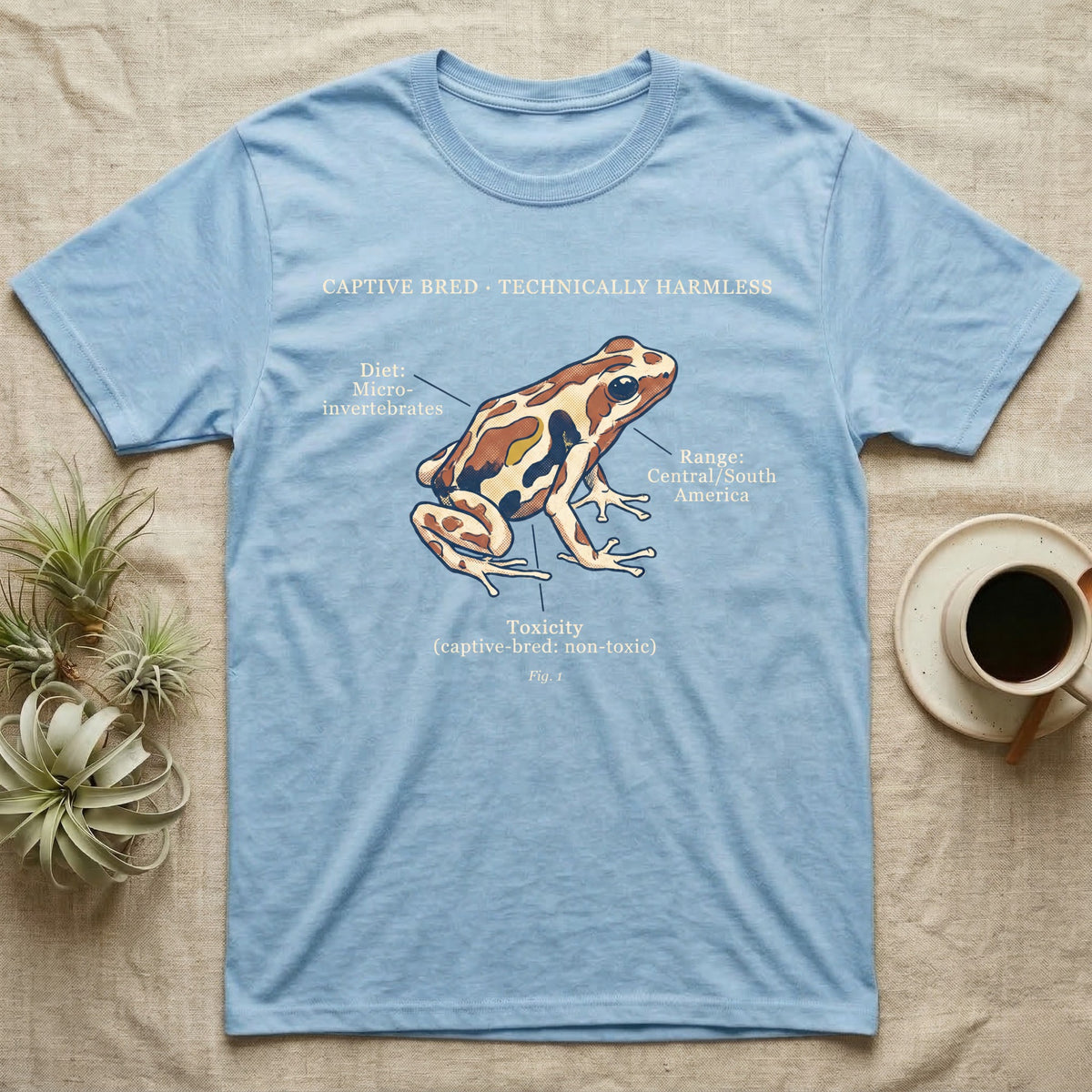 Captive Bred Dart Frog T-Shirt in Light Blue — Retro science-plate illustration of a labeled dart frog with field-guide callouts and a captive-bred non-toxic note.