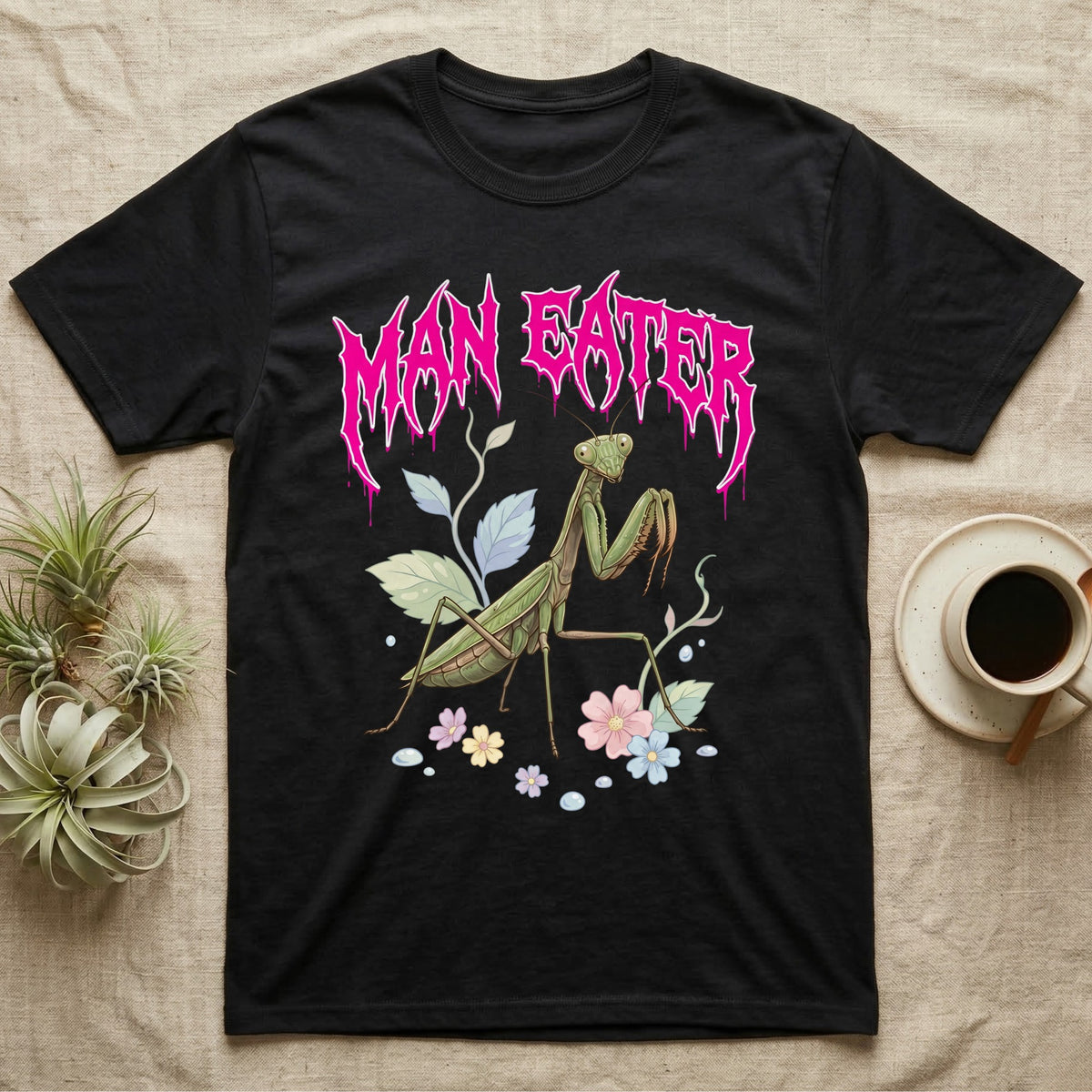 Chinese Mantis Feral T-Shirt in Black — Pastel Chinese mantis with raised spiked forelegs among leaves and blossoms, jagged magenta metal wordmark "MAN EATER" above.
