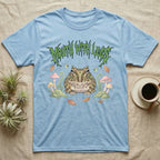 Pacman Frog Feral T-Shirt in Light Blue — Round Pacman frog in a pastel forest-floor scene under a spiky leaf-green metal wordmark reading MOUTH WITH LEGS.