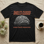 Box Turtle Shell's Closed T-Shirt in Black — Engraved white-line eastern box turtle shut tight under retro orange script reading SHELL'S CLOSED, come back tomorrow.