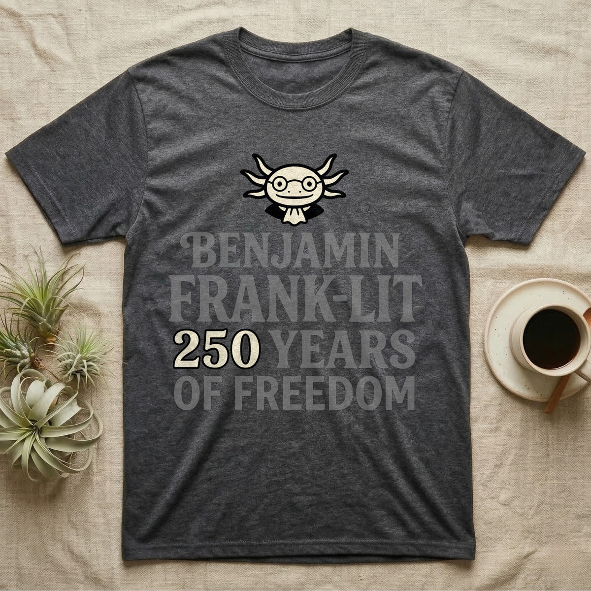 Axolotl Benjamin Franklin T-Shirt in Dark Heather — Flat cream axolotl as Ben Franklin in glasses above bold text reading Benjamin Frank-Lit, 250 Years of Freedom.