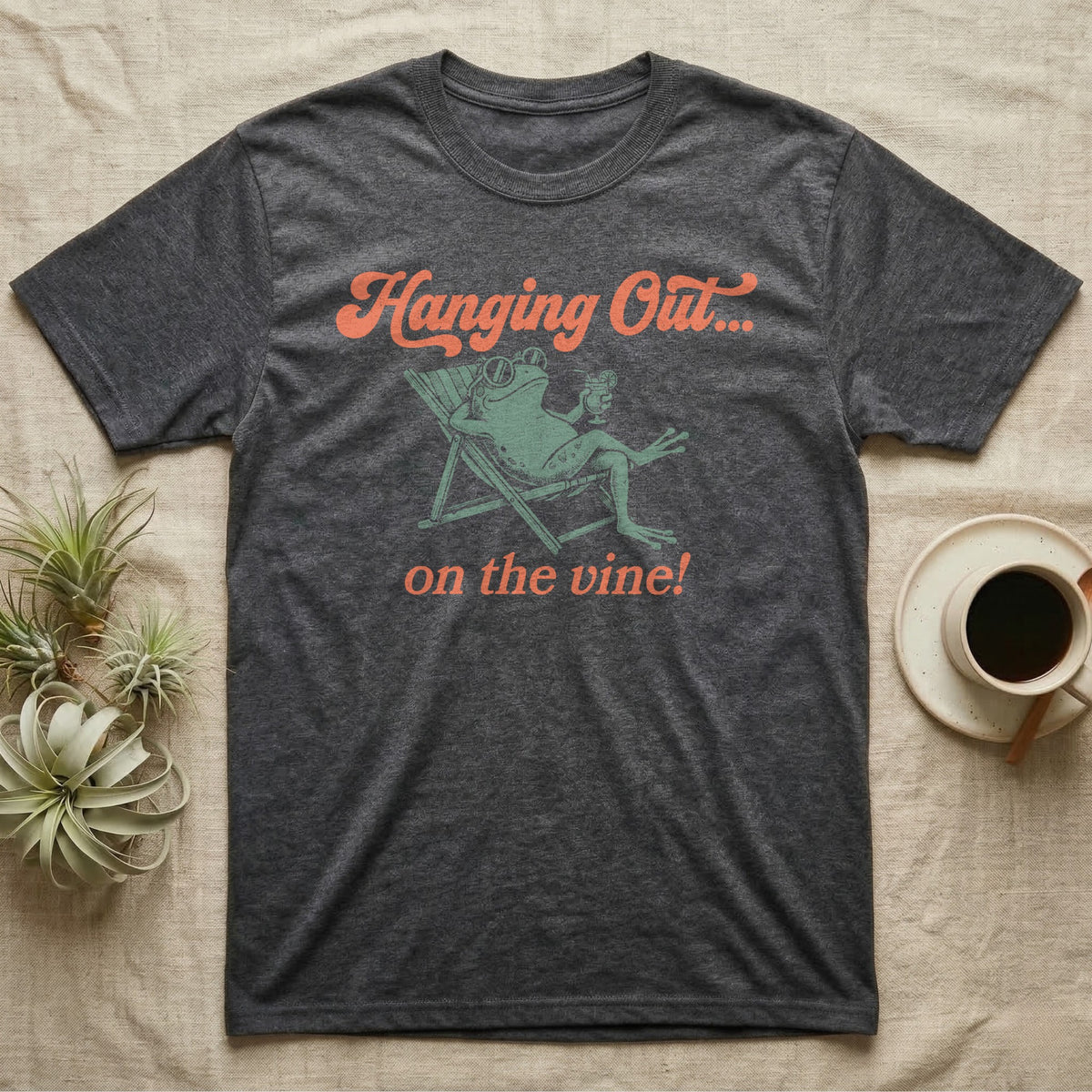 Tomato Frog Vine Vibes T-Shirt in Dark Heather — Illustrated tomato frog reclining in a beach chair with sunglasses and a cocktail, coral script reading Hanging Out On The Vine.