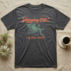 Tomato Frog Vine Vibes T-Shirt in Dark Heather — Illustrated tomato frog reclining in a beach chair with sunglasses and a cocktail, coral script reading Hanging Out On The Vine.