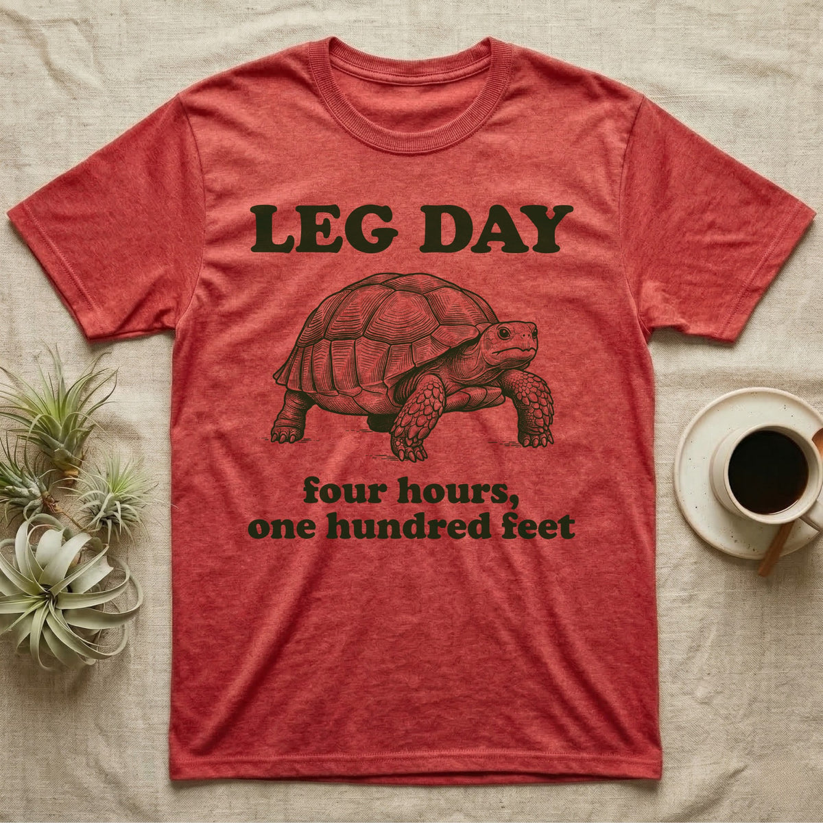 Sulcata Tortoise Leg Day T-Shirt in Heather Red — Engraved sulcata tortoise in deep green ink beneath the words LEG DAY, with four hours, one hundred feet below.