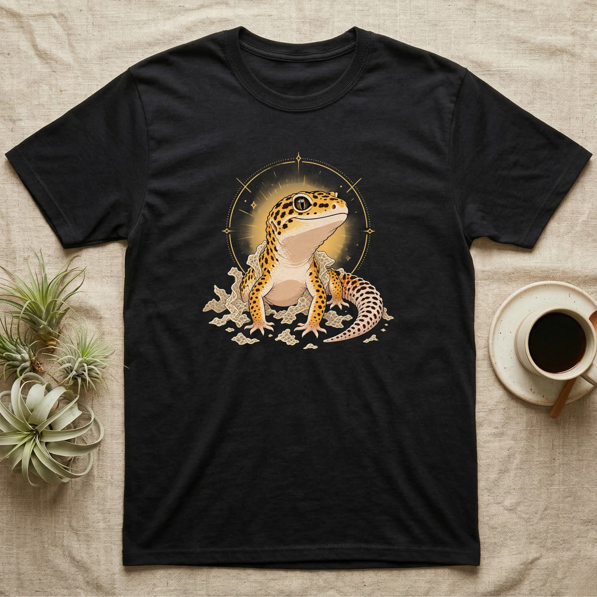 Leopard Gecko Shed T-Shirt in Black — Bold vector illustration of a leopard gecko emerging fresh from a shed, lit by a soft warm halo glow.