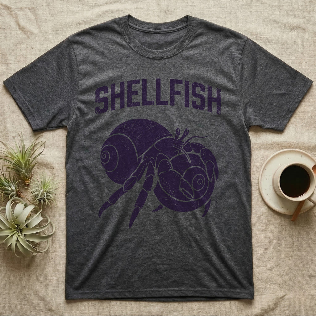 Hermit Crab Shellfish T-Shirt in Dark Heather — Worn purple one-ink print of a hermit crab hugging a big spare shell to its chest under the word Shellfish