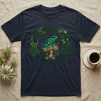 Dark t-shirt with a frog on a mushroom, surrounded by a wreath of leaves.