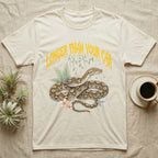 Reticulated Python Feral T-Shirt in Natural — Reticulated python in net-patterned coils under jagged molten-gold metal text LONGER THAN YOUR CAR with pastel ferns