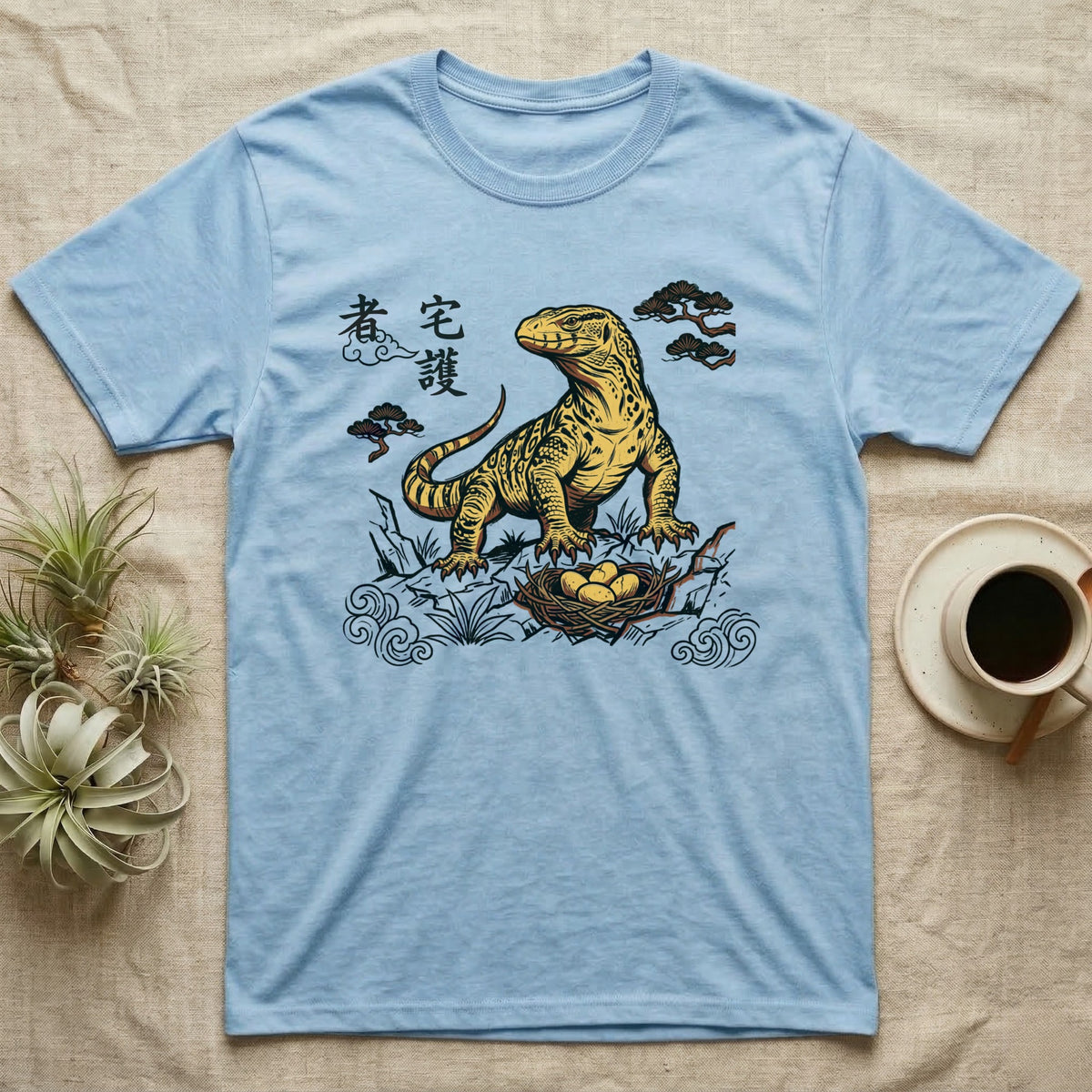 Light blue t-shirt with a yellow monitor lizard and nest graphic.