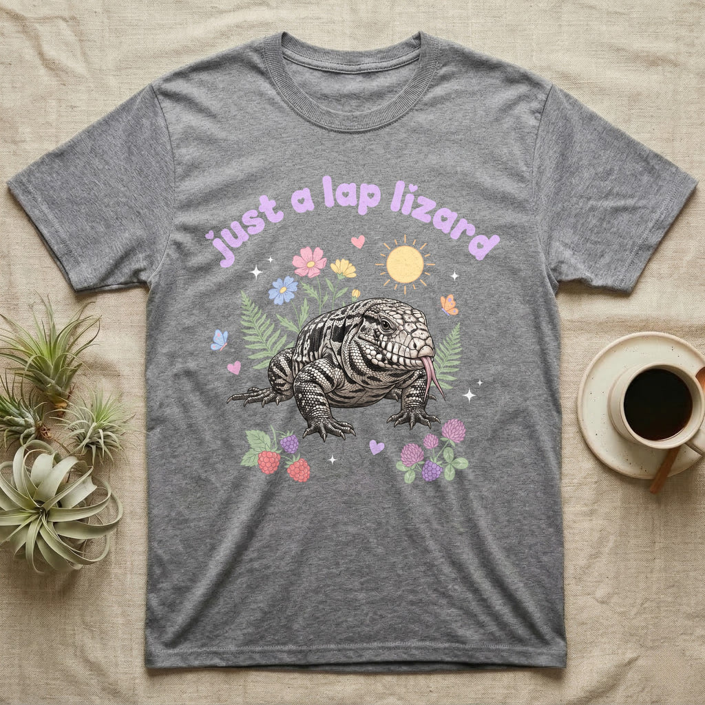 Argentine Tegu Baby T-Shirt in Sport Grey — Black-and-white Argentine tegu with forked tongue among pastel flowers under puffy lavender text "just a lap lizard".