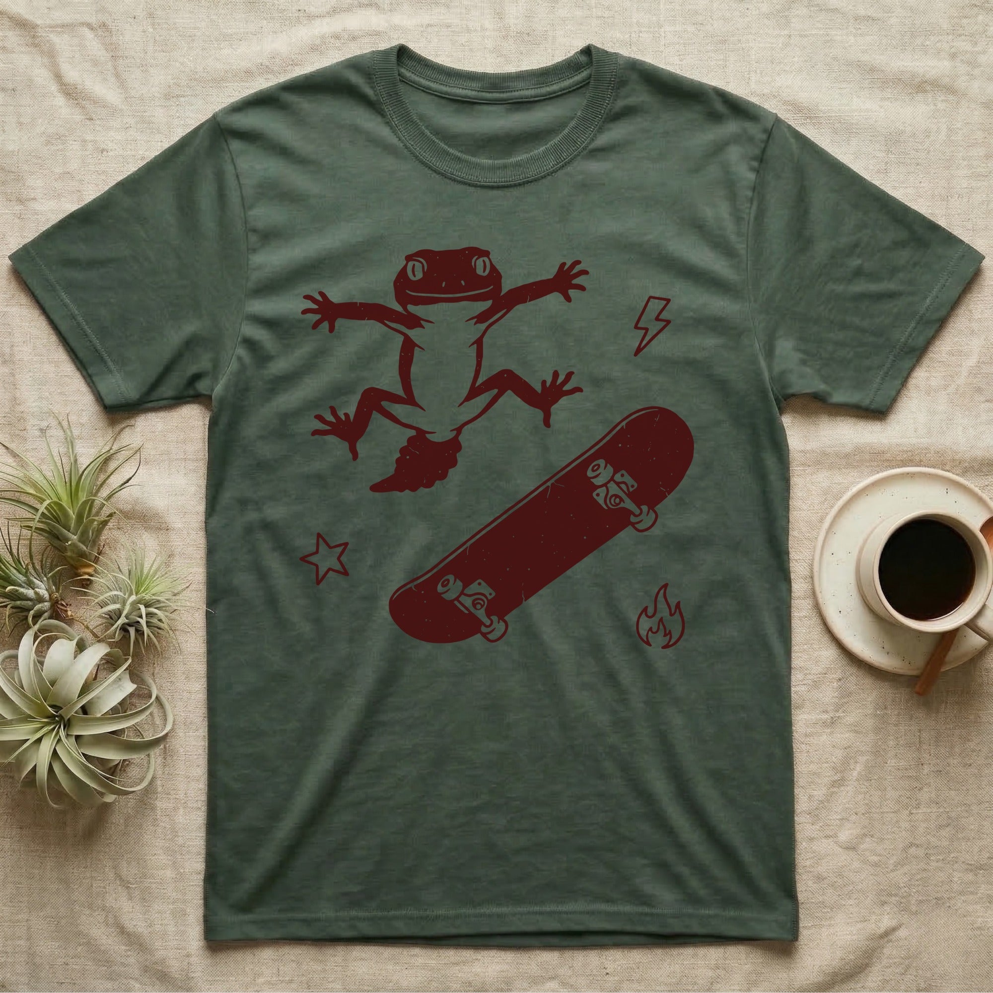 Knob-Tailed Gecko Kickflip T-Shirt in Military Green — Distressed one-ink illustration of a knob-tailed gecko airborne mid-kickflip above a tumbling skateboard.