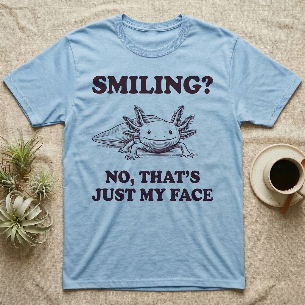 Axolotl Resting Face T-Shirt in Light Blue — Engraved axolotl sitting head-on with gills fanned and a wide smile, with the words Smiling? No, That's Just My Face