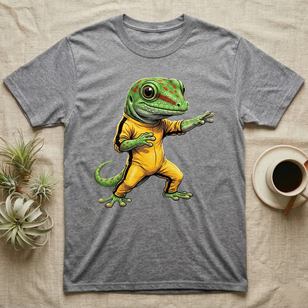Anthropomorphic giant day gecko in a yellow-and-black martial-arts jumpsuit, low fighting stance, bold vintage-comic ink outlines and halftone shading, graphic-only design. — shown on a Sport Grey tee.