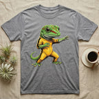 Anthropomorphic giant day gecko in a yellow-and-black martial-arts jumpsuit, low fighting stance, bold vintage-comic ink outlines and halftone shading, graphic-only design. — shown on a Sport Grey tee.