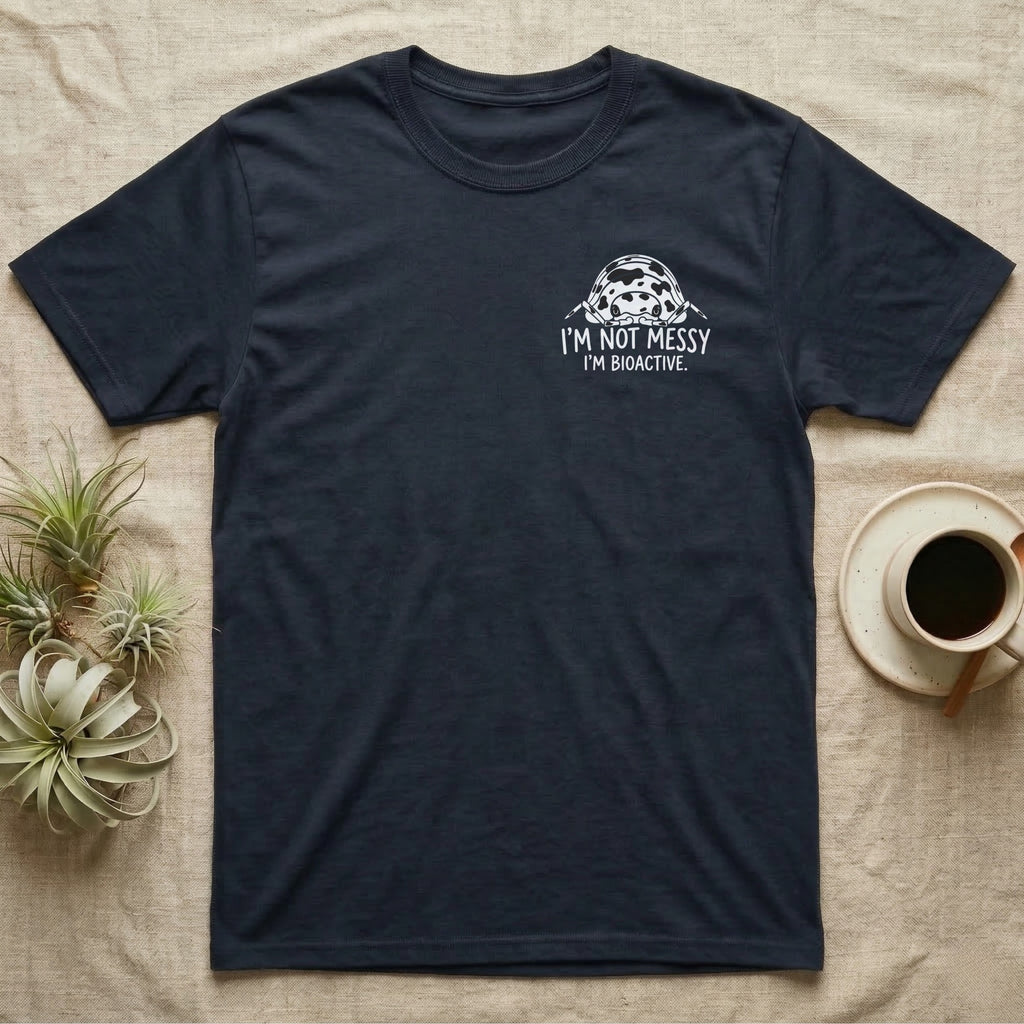 Bioactive Dairy Cow T-Shirt in Navy — White dairy cow isopod with black cow patches peeking over white marker capitals reading I'M NOT MESSY I'M BIOACTIVE.
