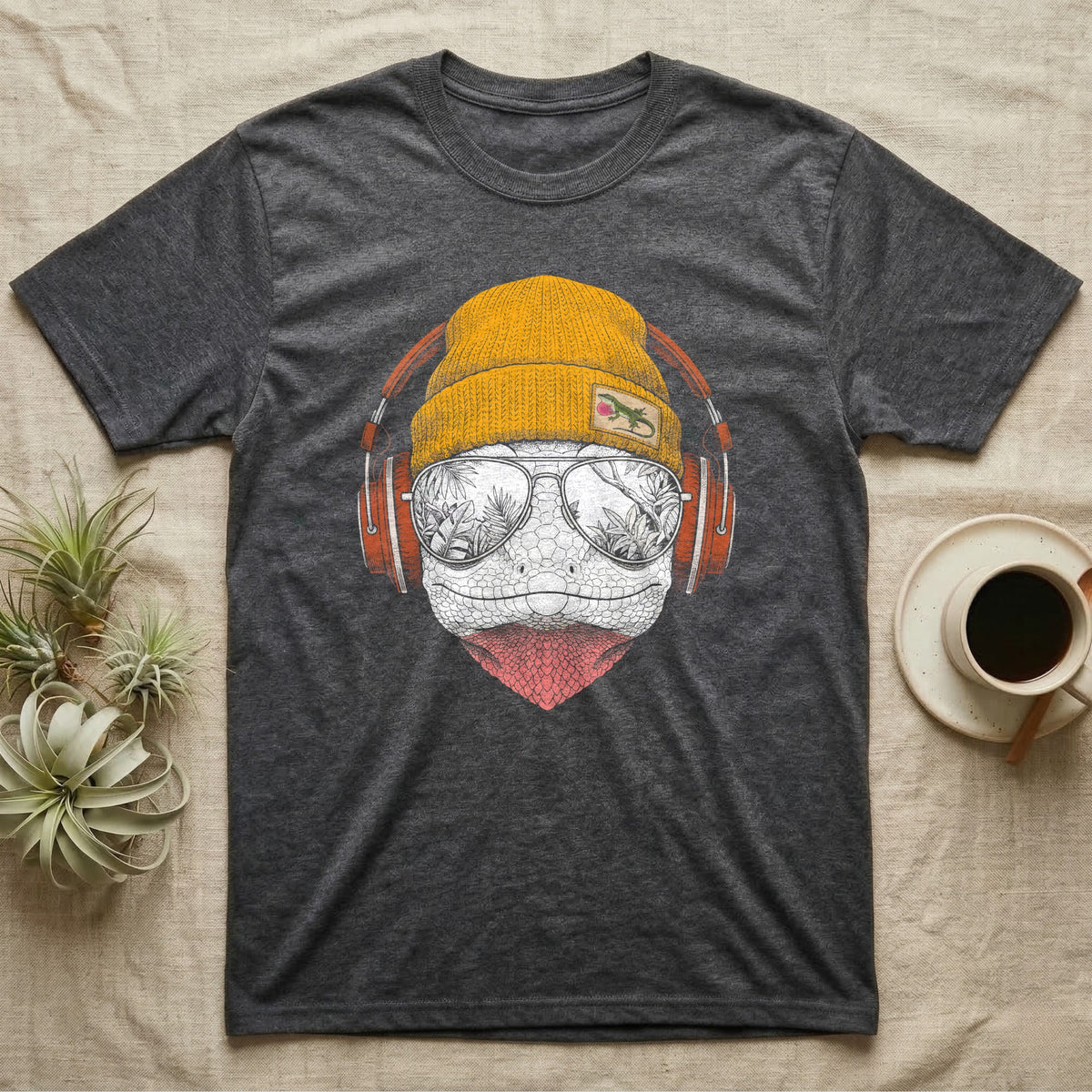 Green Anole Chill Beats T-Shirt in Dark Heather — Engraved green anole with pink dewlap showing, in a beanie and headphones, aviators reflecting tropical palms.