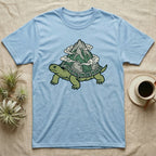 Light blue t-shirt featuring a cartoon turtle with a mountain on its shell.